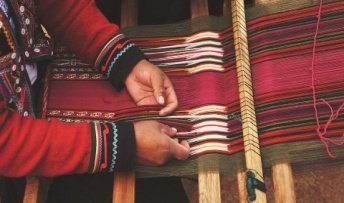 A Native American making clothing on a loom