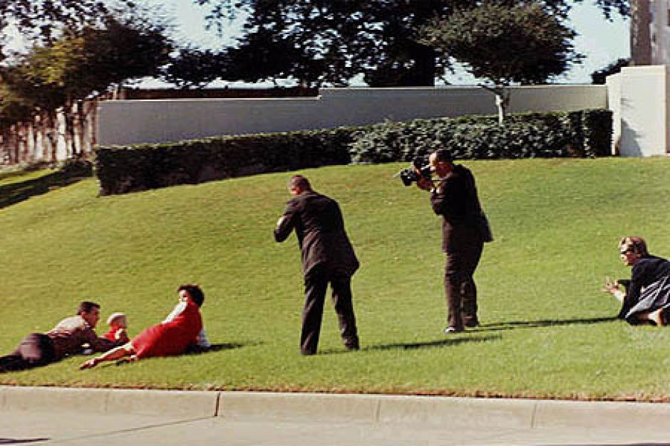 People dive for cover on the grassy knoll. - ABC News (Australian Broadcasting Corporation)