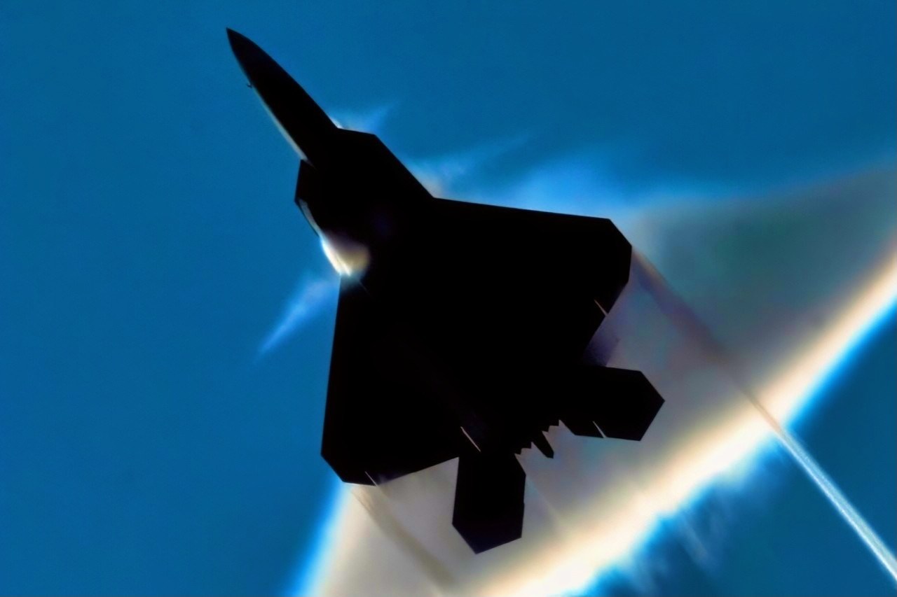 An Air Force F-22 Raptor executes a supersonic fly by over the flight deck of the aircraft carrier USS John C. Stennis. John C. Stennis is participating in Northern Edge 2009, a joint exercise focusing on detecting and tracking units at sea, in the air and on land.