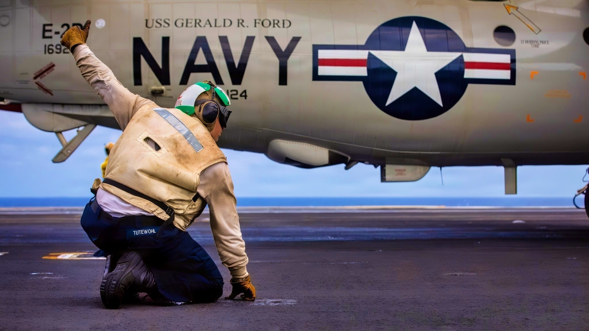 A U.S. Sailor, assigned to Airborne Command and Control Squadron 124, signals the launch of a Carrier Air Wing 8 E-2D Hawkeye aircraft on the flight deck of the world's largest aircraft carrier, Ford-class aircraft carrier USS Gerald R. Ford (CVN 78), while underway in the Caribbean Sea, Nov. 29, 2025. U.S. military forces are deployed to the U.S. Southern Command area of responsibility in support of Operation SOUTHERN SPEAR, Department of War-directed operations, and the president's priorities to disrupt illicit drug trafficking and protect the homeland. (U.S. Navy photo)