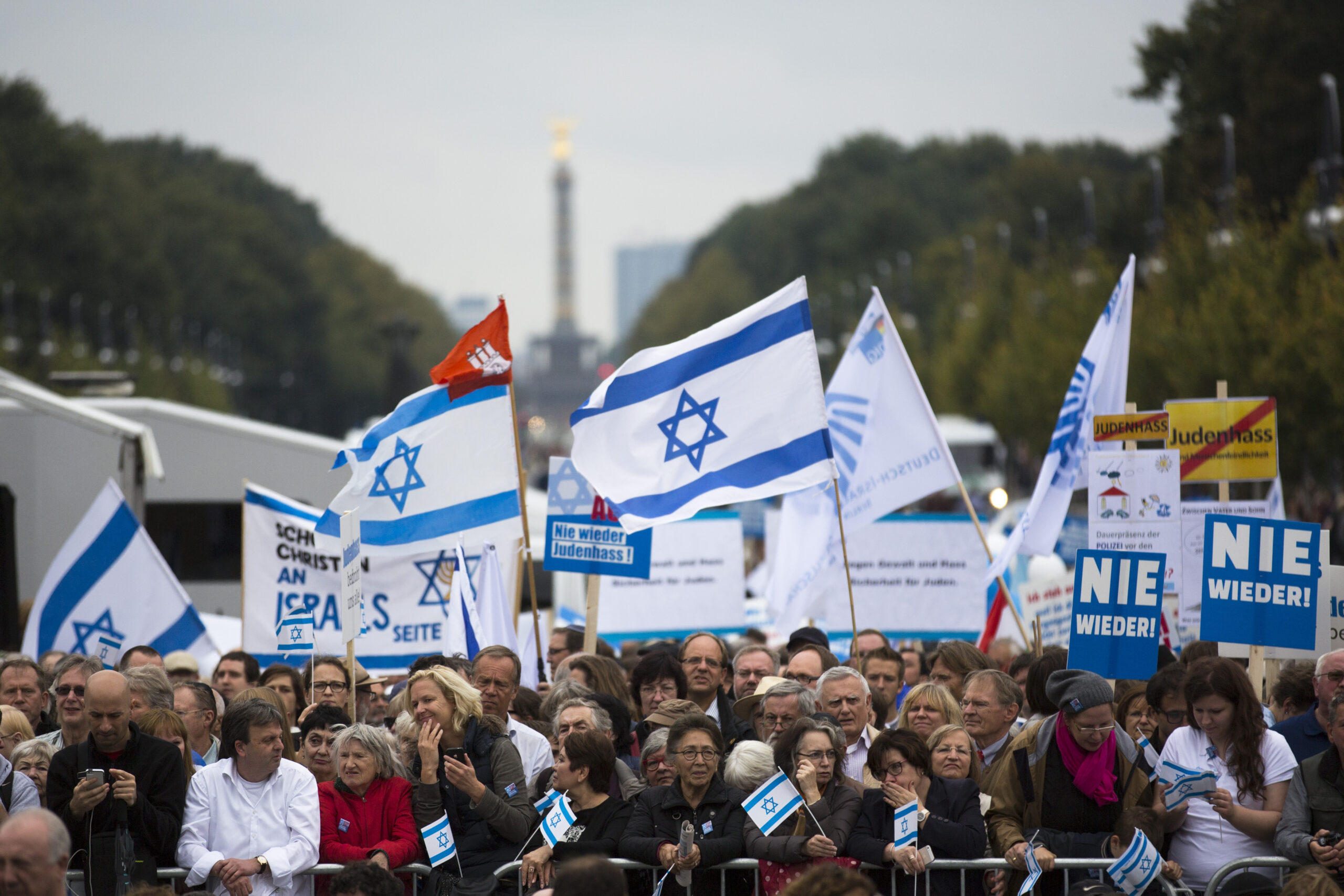 People with Israeli flags and banners, reading 'never again' , right, attend a rally against anti-Semitism near the Brandenburg Gate in Berlin.